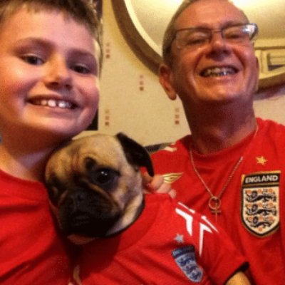Chris and Ross wearing football shirts, smiling and holding a pug