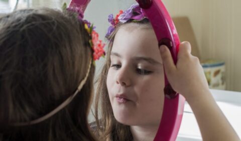Young girl examining herself in a mirror