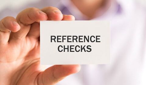 A person holding up a paper card that says 'Reference Checks'