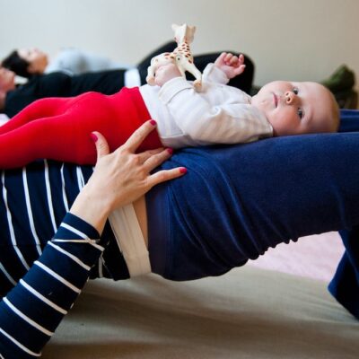 parent performing a glute bridge using baby as additional weight