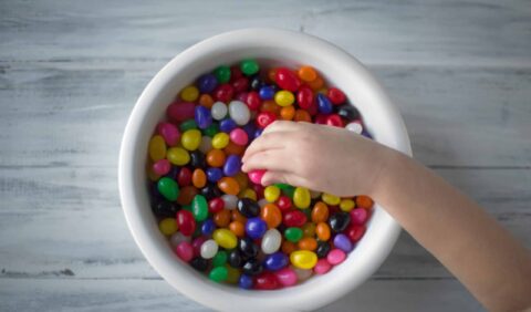 A child picking from a bowl of sugary sweets