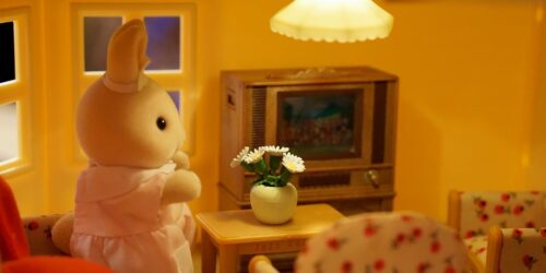 A toy bunny in a dress in a doll house