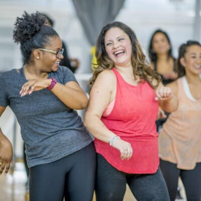 Two adult women having fun dancing together as part of an exercise class