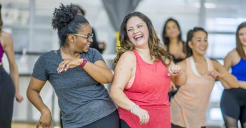 Two adult women having fun dancing together as part of an exercise class