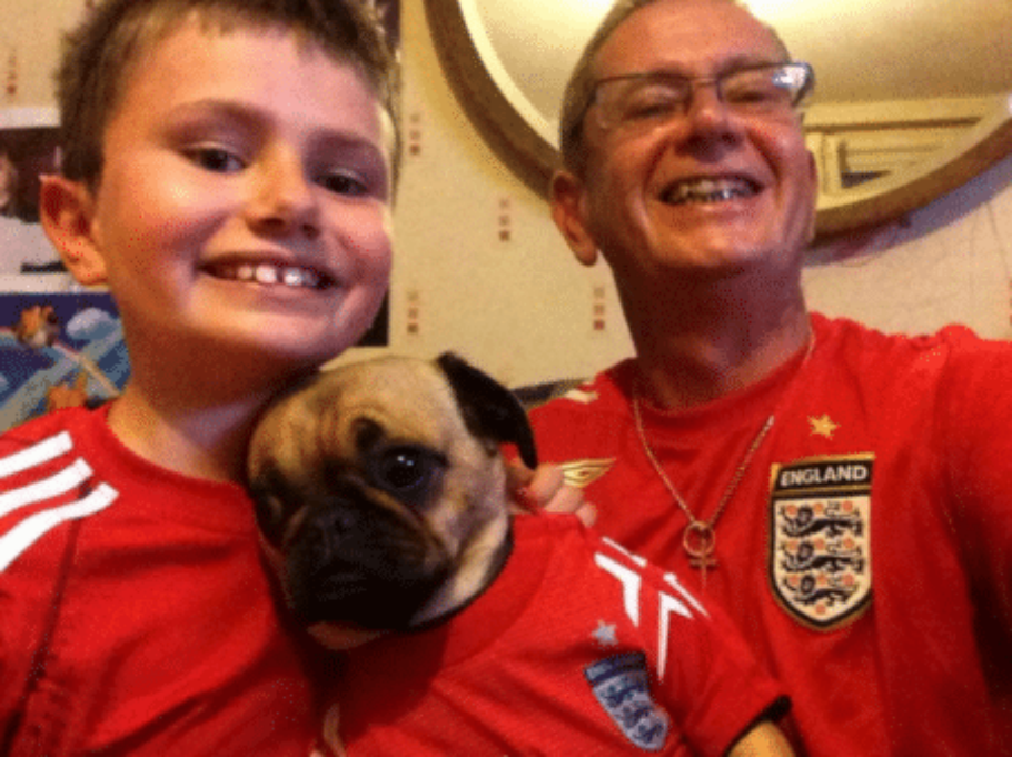 Chris and Ross wearing football shirts, smiling and holding a pug
