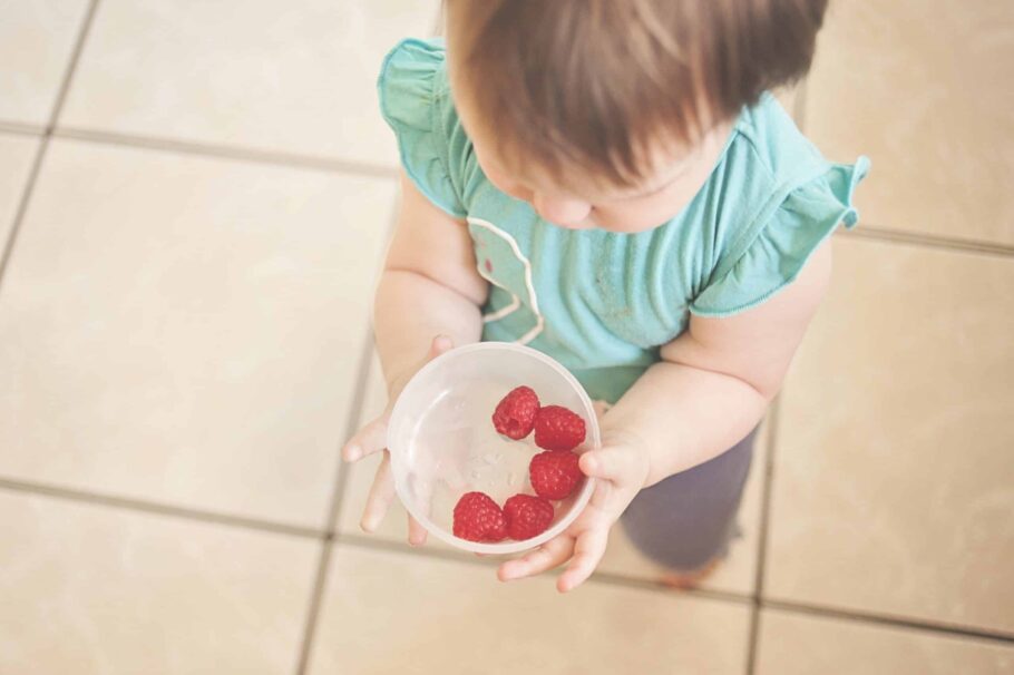 Baby holding a bowl of fruit