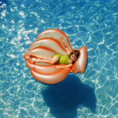 Child enjoying floating around on a pool float shaped like a clam