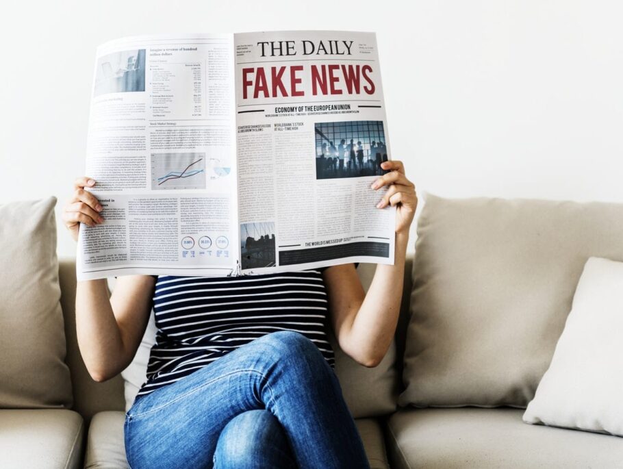 A woman holding up a newspaper with the headline Fake News