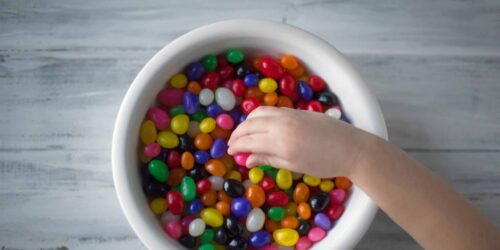 A child picking from a bowl of sugary sweets