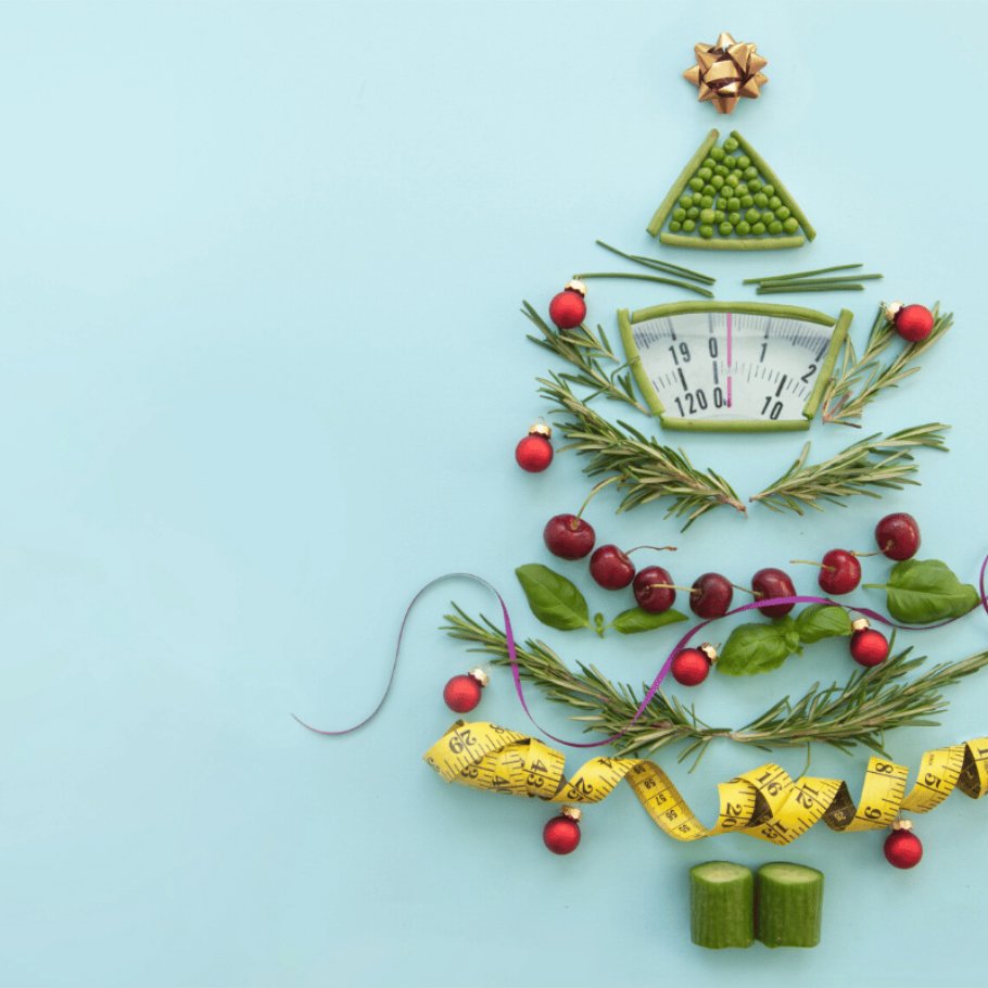 A christmas tree built from vegetables, herbs and measuring tape on a blue background