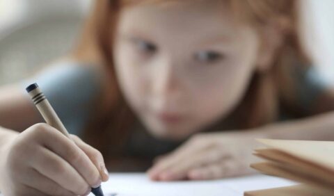 A young girl drawing with a crayon