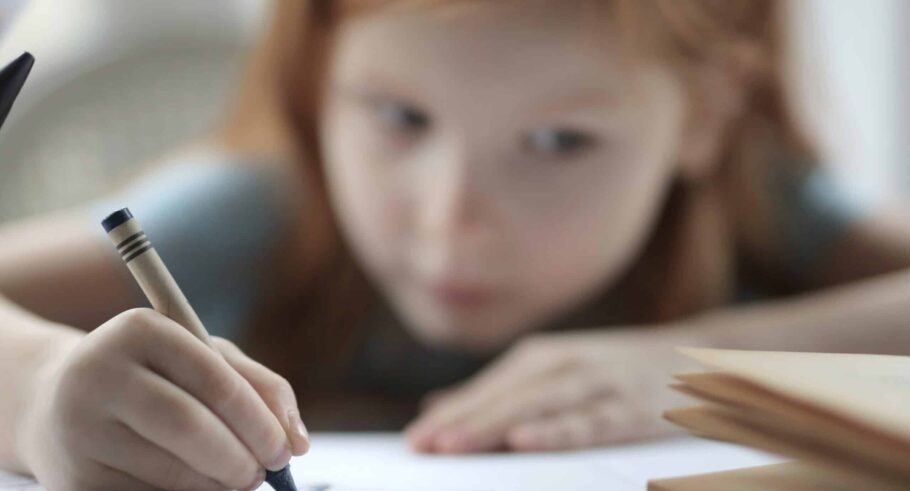 A young girl drawing with a crayon