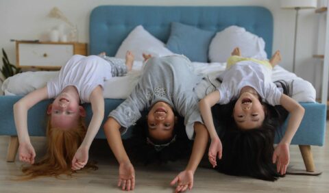 Children having fun hanging upside down on a bed