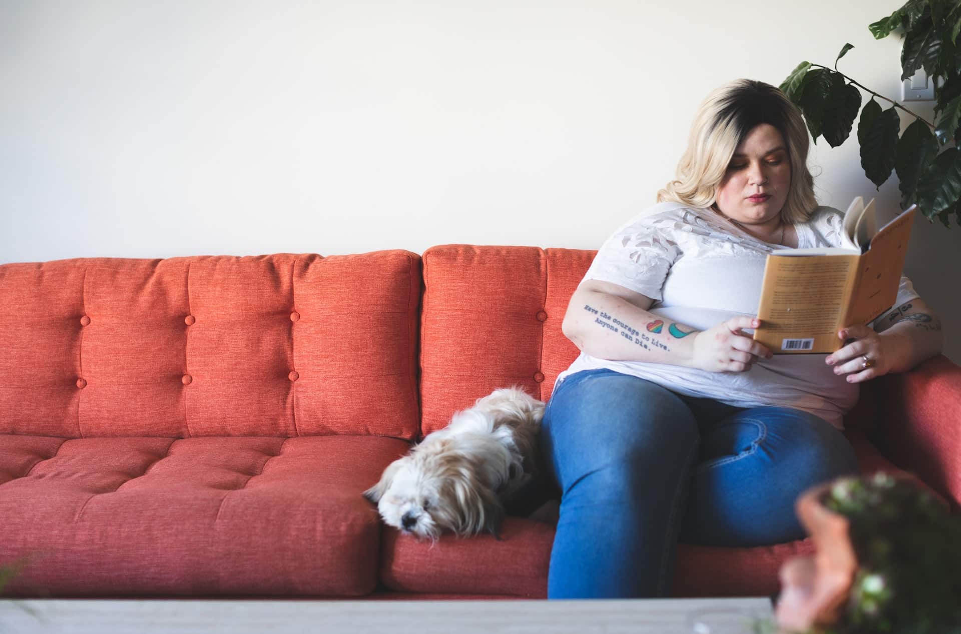 Overweight woman reading with her dog on the sofa