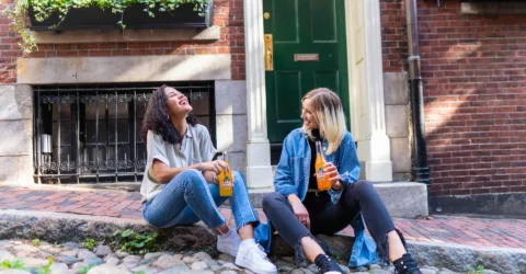 Two teenagers drinking soft drinks on the street